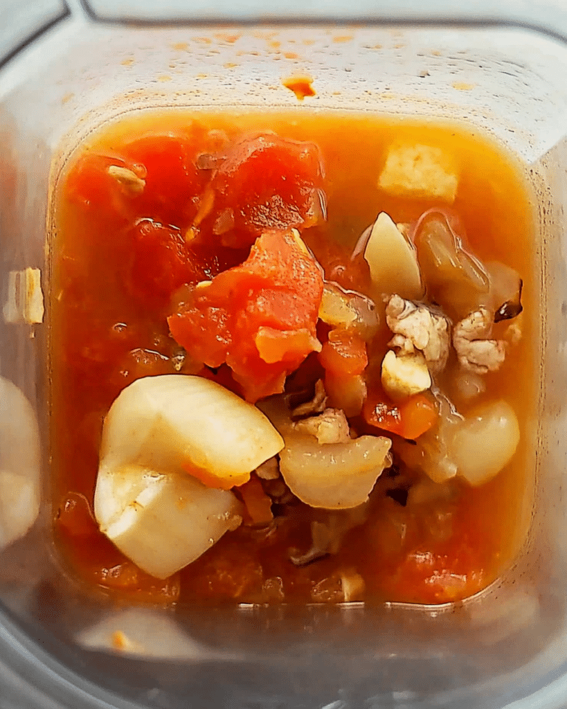 Sautéed onion and tomato mixture in a blender jar.