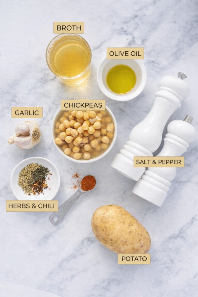 The ingredients to make this vegan garlic chickpea soup are arranged over a white table.